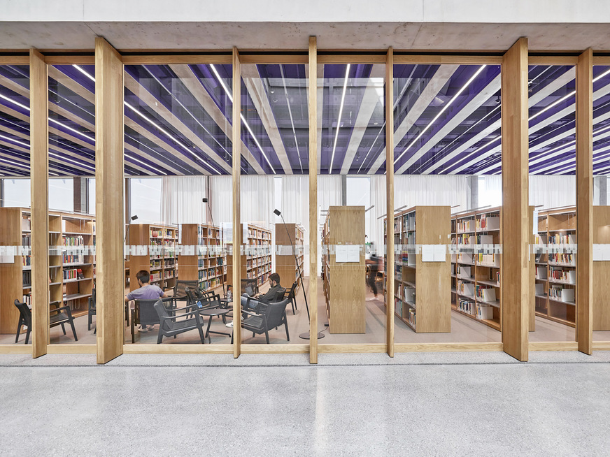 Blick vom Atrium in die Bibliothek auf der „Beletage“ im dritten Obergeschoss. Auch hier sind die Überströmelemente in die Trennwände integriert.