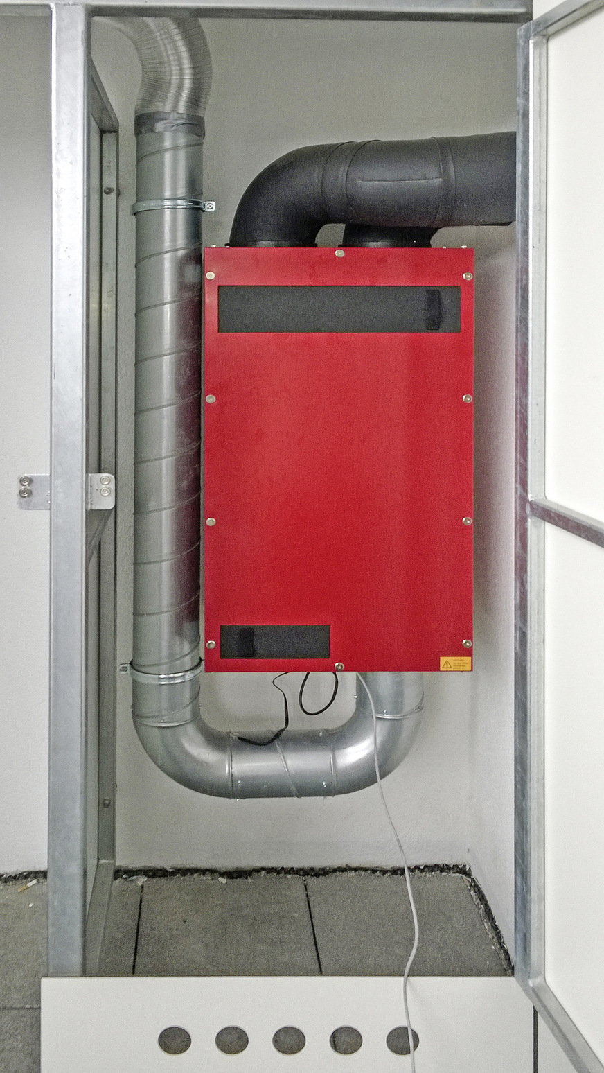Blick auf das Wohnungslüftungsgerät im Installationsschrank mit Frischluftansaugung aus dem Schrank.