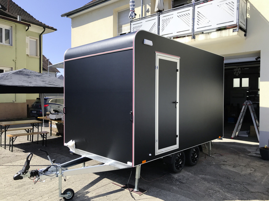 Jungfräulich in mattem Schwarz steht der Hänger vor der Werkstatt.