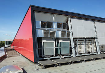 Die Wärmepumpen-Außengeräte stehen unter einem Schutzdach auf dem begrünten Flachdach und sind zusätzlich mit Sonnensegeln gegen Überhitzung geschützt.