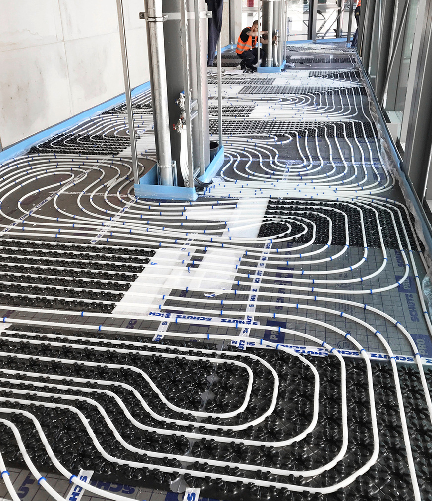 An der Oberseite der schwarzen Airconomy-Systemmodule mit Wärme- und Trittschalldämmung werden die Heizrohre über Nocken fixiert.