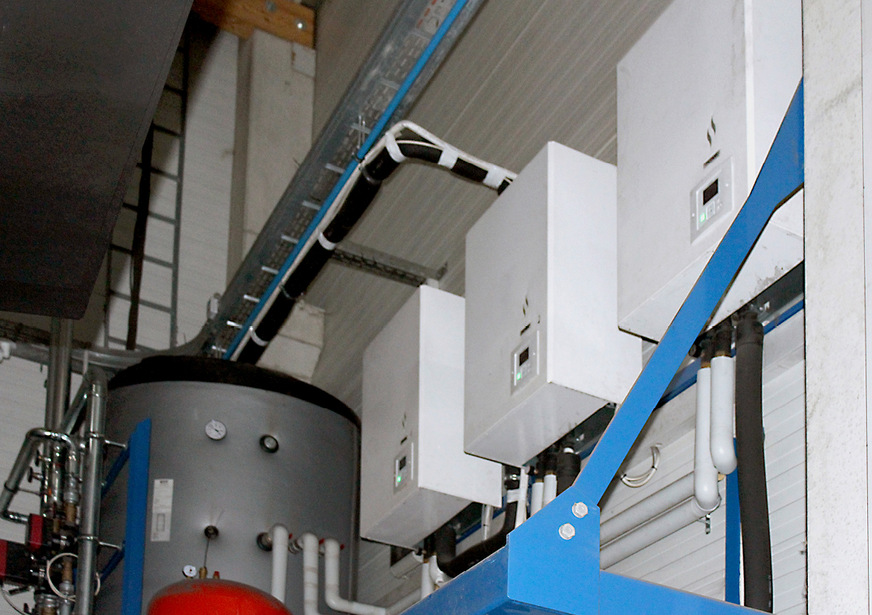 Die Wärmepumpen-Inneneinheiten sind an der Wand montiert. Links unten der Pufferspeicher.