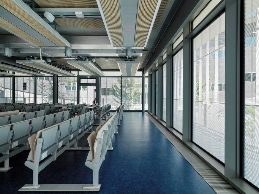 Die Kühlpaneele sind in eine multifunktionale Struktur integriert, die aus hölzernen Seitenwänden mit Akustikfunktion und beidseitigen LED-Lichtleisten besteht. Dazwischen wurden alle Anlagen bewusst sichtbar gelassen.