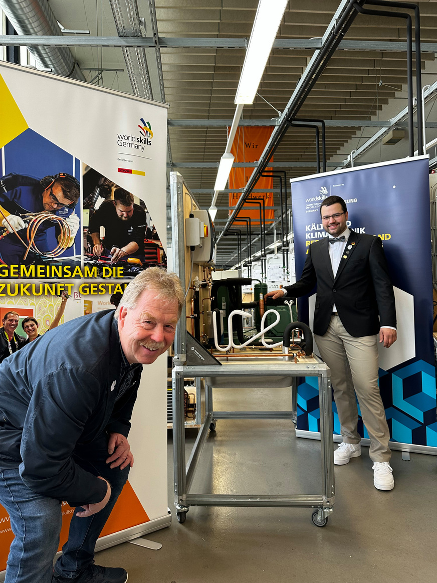 Frederik Stiegen und Karsten Beermann vor der Kälteanlage mit dem Schriftzug “ice“ aus dem Wettbewerb 2022 in Nürnberg, die vom IKKE an Frederik Stiegen übergeben wurde, als Belohnung für die guten Leistungen.