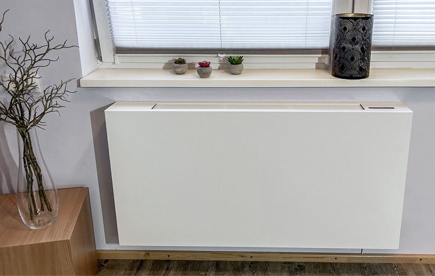 Der Wärmepumpenheizkörper PowerKon LT integriert sich durch seine flache Bauweise gut in den Raum, Vor- und Rücklaufleitungen verschwinden in der Verkleidung. Die Luftansaugöffnung ist unsichtbar an der Unterseite platziert. Die Front hat daher eine ansprechende glatte Optik, die an einen Planheizkörper erinnert.