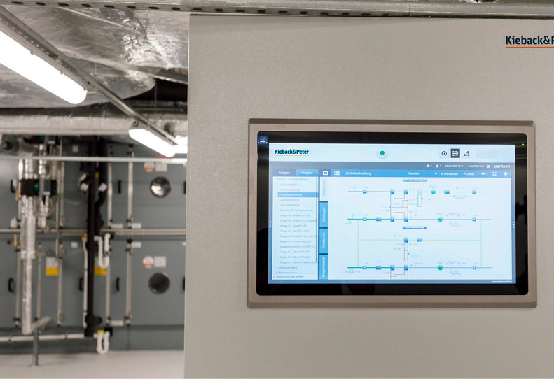 Eine von drei Technikzentralen: Diese ist für den Bereich Lüftung installiert worden. Im Hintergrund: Zonengeräte der Lüftungsanlage. Rechts: Die intuitiv bedienbare Benutzeroberfläche von Qanteon, die über einen 22“-Panel-PC zur Überwachung des technischen Gebäudebetriebs dient.