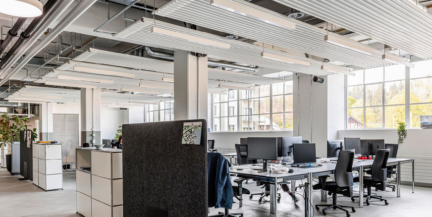 Modernes Co-Working: Die Deckenstrahlplatten von Zehnder sorgen im Sommer für angenehme Arbeitstemperaturen, verbessern die Akustik und betonen den industriellen Look.