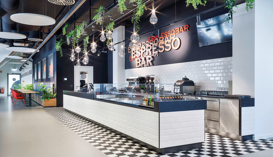 In der Espressobar sind Drall-Luftdurchlässe Indudrall von Kiefer als Sichtmontage zwischen den Akustikelementen der Decke integriert. Sie fügen sich in das offene Deckenkonzept ein und bewirken eine gleichmäßige Frischluftzufuhr.