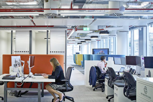 Die lichtdurchflutete Bürolandschaft profitiert von der vergrößerten Raumhöhe. Sie entstand durch das Entfernen der Zwischendecke sowie durch die Freilegung der Deckenkonstruktion inklusive technischer Einbauten.