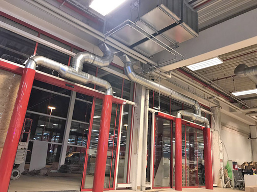 Kombination einer Luftwandanlage an zwei Großtoren eines Baumarktes. Die sensible Luftwandtechnik ist hier im Deckenbereich untergebracht und vor Anfahrschäden geschützt. Die seitlich stehenden Druckdüsensäulen sind noch ohne die später installierten Rammschutzbügel zu sehen.