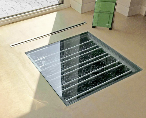 Durch ein Fenster im Fußboden können sich die Ausstellungsbesucher ein Bild vom System Airconomy machen. Durch einen unauffälligen Lüftungsschlitz unter dem Fenster strömt zugluftfrei die vorgewärmte oder gekühlte Frischluft in den Raum.