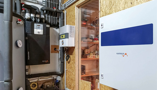 Die eXergiemaschine (schwarzes Gerät links im Bild) hebt die von der Wärmepumpe gelieferte Temperatur auf ca. 65 °C an. Der Systemregler (rechts) dient der Überwachung aller Quellen und optimiert die Heizkreise.