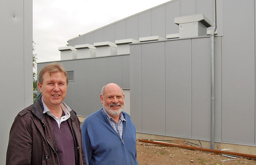 Bauherr Barthel Krosch (rechts) mit Installateur Robert Becker vor dem 
Hallenteil, auf dessen Dach die Wärmepumpen ihren Dienst verrichten.
