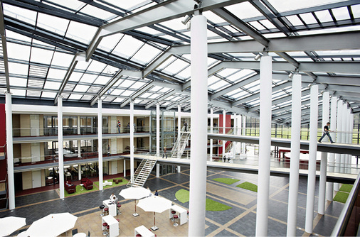Ein zentral angeordnetes, lichtdurchflutetes Atrium fungiert als 
Eingangsbereich und verbindendes Element zwischen den einzelnen 
Gebäudeteilen gleichermaßen.

