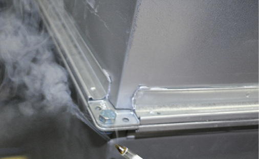 
Bild 3: Leckagestelle an der Flanschverbindung einer rechteckigen Luftleitung 
bei Prüfung auf Undichtheit mit Überdruck, die mit Prüfnebel sichtbar 
gemacht wurde

