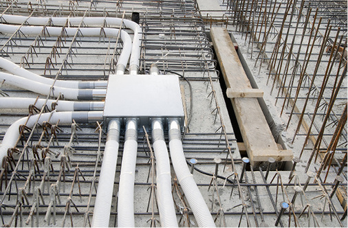 Einbau der Einlegeverteiler und des Einlegerohrsystems pro Geschossdecke. 
Daneben der separate Schacht für die Wärmeübertrager.

