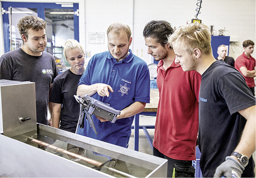 
Bild 1: Jonas Heile (Mitte), einer der Entwickler und Programmierer der 
Prüfvorrichtung für Hartlötverbindungen auf Ultraschallbasis, erklärt den 
Auszubildenden die Messergebnisse auf dem tragbaren Auswertegerät.

