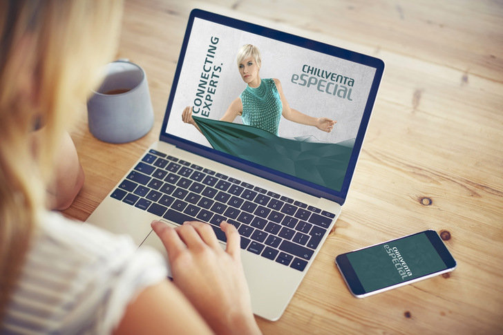 Over the shoulder view of woman using laptop with blank screen. Female blogger is working at home. Smart phone and coffee cup are lying on wooden table.