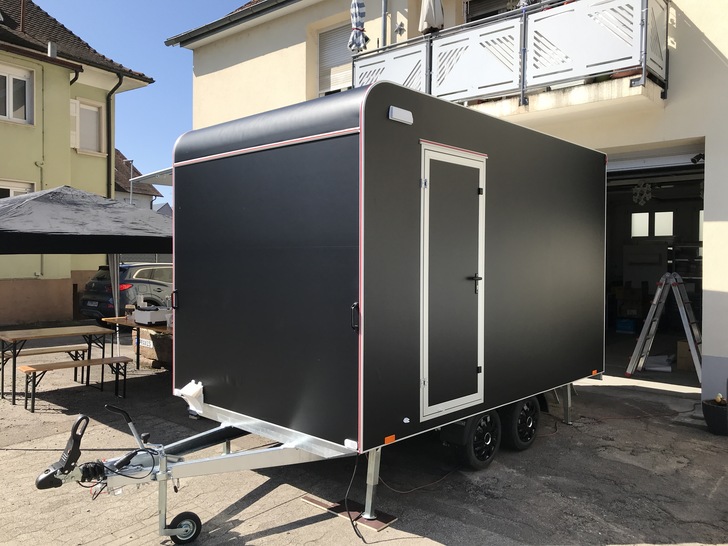 Jungfräulich in mattem Schwarz steht der Hänger vor der Werkstatt.