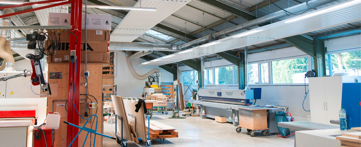 Die Deckenstrahlplatten verteilen die Wärme gleichmäßig und sorgen so für ein besseres Raumklima in der Schreinerei, indem sie im Winter heizen und im Sommer kühlen.