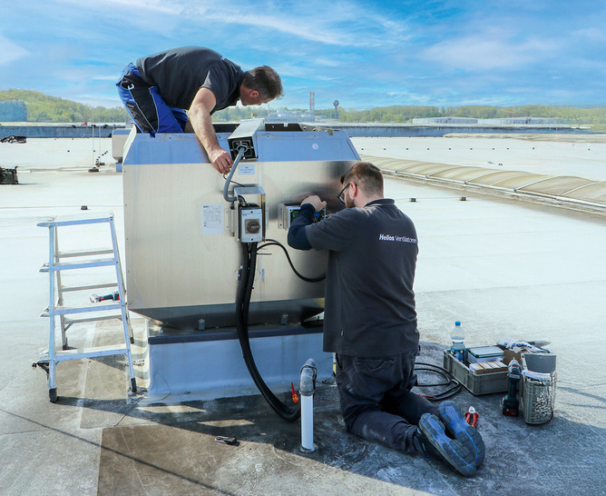 Montage der Lager-Zustandsdiagnostik (LZD):  Servicetechniker rüsten einen Brandgas-Dachventilator vor Ort mit der intelligenten LZD aus.