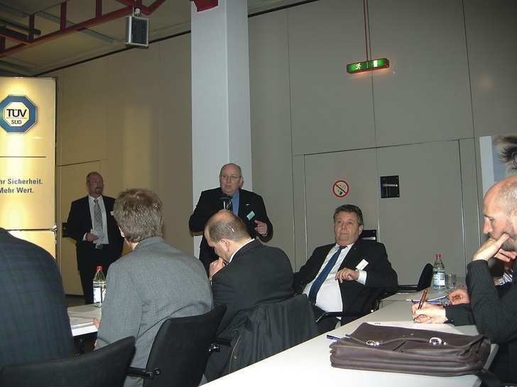 Unter der Moderation von Andreas Hilden (links stehend) fand die diesjährige ATP- und Transfrigoroute-Fach­tagung über die Einhaltung der Kühlkette im Lebens­mitteltransport beim TÜV-Süd statt. Im Bild (rechts stehend) Konrad Etteler, der über Erfahrungen aus dem Bereich Lebensmittelkontrollen in NRW berichtete