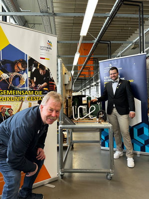 Frederik Stiegen und Karsten Beermann vor der Kälteanlage mit dem Schriftzug “ice“ aus dem Wettbewerb 2022 in Nürnberg, die vom IKKE an Frederik Stiegen übergeben wurde, als Belohnung für die guten Leistungen.