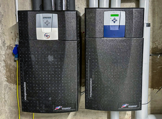 Die eXergiemaschine zum Anheben der Abwärmetemperatur auf ein nutzbares Niveau liegt als kompaktes Wandgerät (links im Bild, rechts daneben ein hydraulischer Durchlauferhitzer) und als etwa kühlschrankgroßes Standgerät mit Leistungen von 3 bis 40 kW vor. 
 Die Nutzung der eXergiemaschine (links) setzt den Einsatz eines Heizspeichers (rechts) voraus, wie er in den meisten Wärmeanlagen ohnehin vorhanden ist.