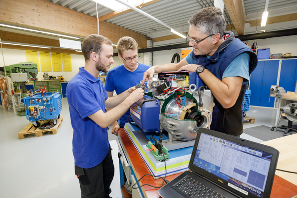 Ausbilder Wolfgang Steur erklärt den beiden Auszubildenden das Schnittmodell des Turbocor-Verdichters das Herzstück der Quantum-Kältemaschinen.