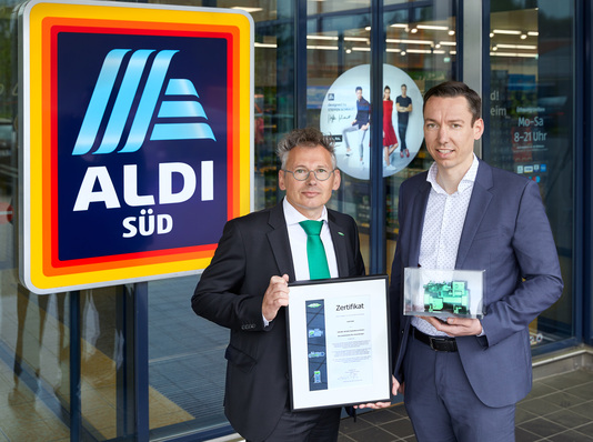 Erik Bucher (Director Sales Refrigeration bei Bitzer) übergibt das Modell eines Hubkolbenverdichters sowie ein Zertifikat an Jens Straßburg (Director Store Operations Management bei ALDI SÜD)